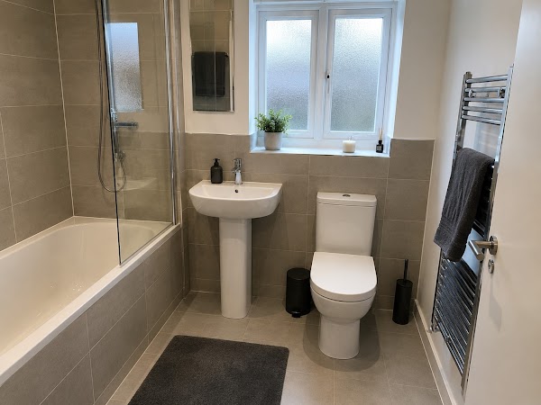 Immaculate bathroom with clean bath, shower screen and tiles